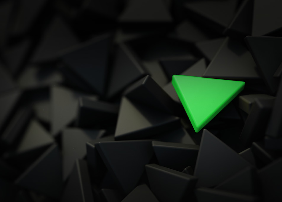 Grünes Dreieck auf einem Haufen schwarzer dreieckiger Steine